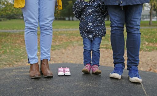 A family standing next to each other, including the mother, father, child and the baby they are expecting