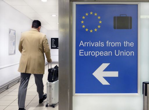 A wide angle shot of an airport sign welcoming people arriving from the European Union next to a person