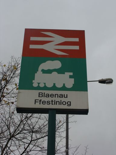 A vertical shot of a railroad sign in green and red placed outside