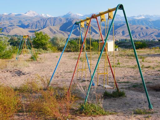 A wide angle shot of a metal swing of multiple colors in front of the mountains