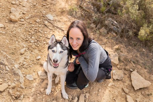 A high angle shot of a young happy female with blue eyes posing next to her husky