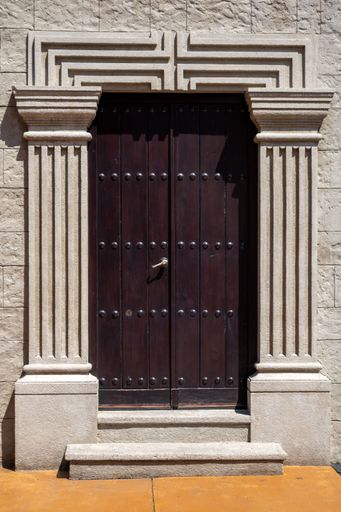 A vertical shot of an old wooden door of a stone building with sunlight
