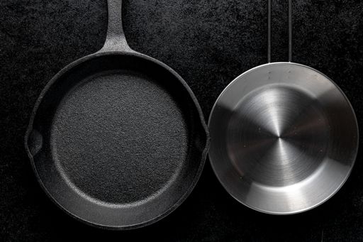An overhead shot of two metal frying pans on a black background