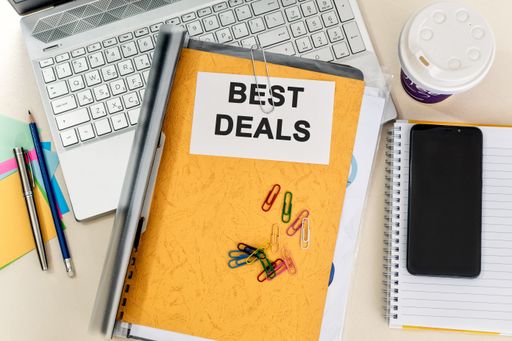 A top view of a yellow folder labelled "BEST DEALS" on a laptop in the office