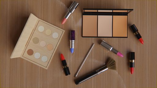 A lash lifting tool, colorful lipsticks, brushes, eyeshadow and contour palettes on the table