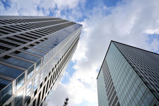 A low angle shot of modern glass skyscrapers against the cloudy sky