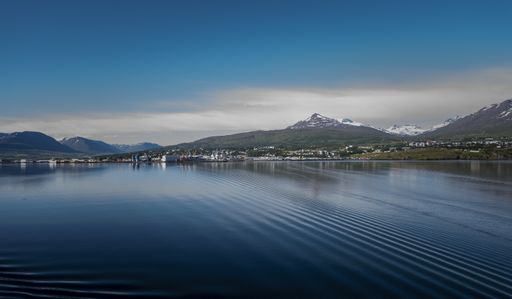 A mesmerizing view of Akureyri, Iceland on the shore of a clear lake with snowy mountains in the background