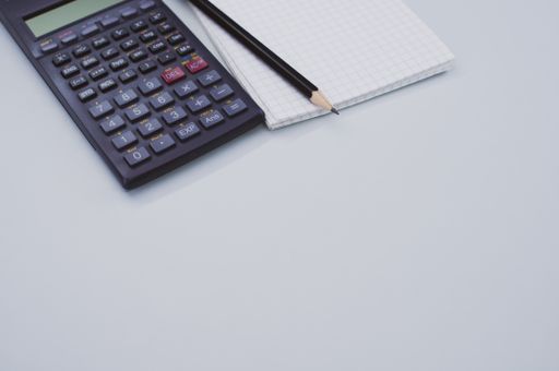 A high angle shot of a scientific calculator, pencil, and math notepad isolated on white background