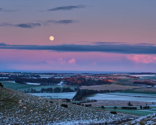 The full moon glowing in the sky above s small town. Leven, Scotland.