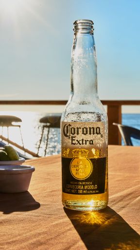 A vertical shot of a  frosty bottle of Corona Extra beer on a wooden table