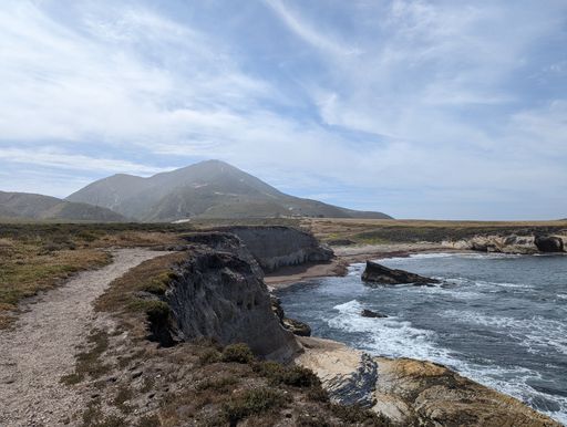 A scenic view of a rocky coastline with wavy sea under the blue sky