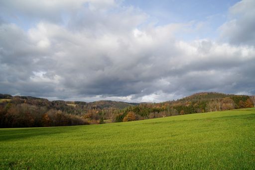 A landscape of hills covered in greenery under a cloudy sky on a rainy day in the countryside