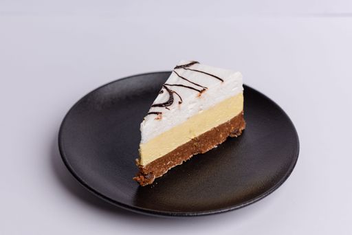 A delicious dessert of a single slice of cheesecake on a matte dark grey plate on a white background