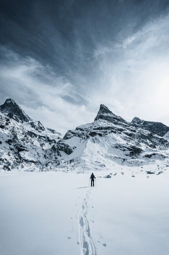 A highlander walking alone in the pristine snow of Swiss mountains to the Mont Mine