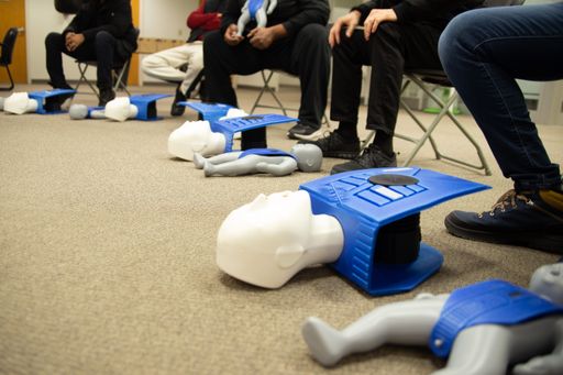 A classroom of students learning the basics of first aid with a doll