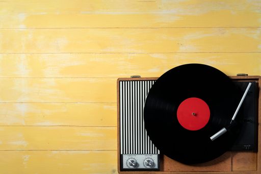 Old gramophone with a vinyl record on yellow wooden table