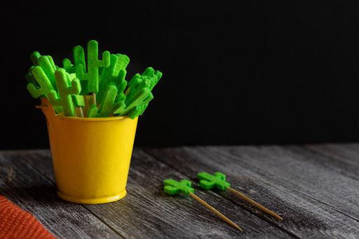 A closeup shot of a yellow bucket filled with cactus-shaped toothpicks