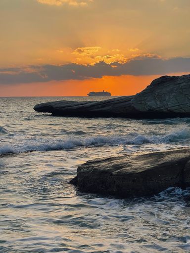 A landscape view of water splashing on rocks with orange sunset scene, vertical shot