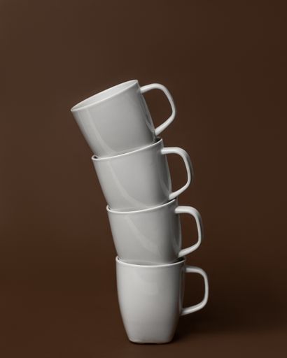 A vertical closeup of white-colored mugs placed on top of each other