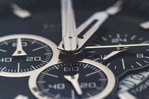 A closeup shot of the hands, numbers and hour marks of a black watch