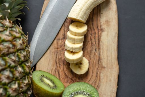 A high angle shot of chopped banana, kiwi and pineapple on a cutting board