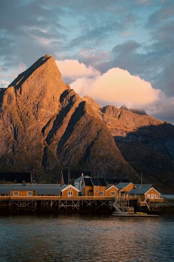 A vertical shot the houses on the bridge over the sea with rocky mountains in the back