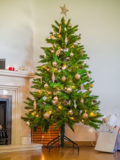 A vertical picture of a Christmas tree decorated with lights and ornaments in a house