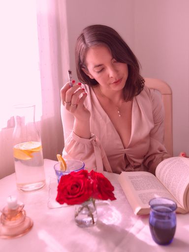 Young millennial woman enjoying a THC/CBD joint and book with pink filter.
