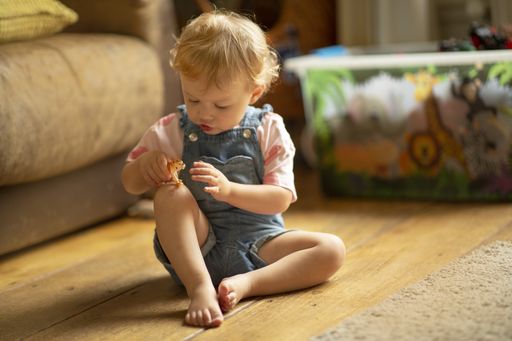 A little child playing with a small toy while sitting on the floor in the living room