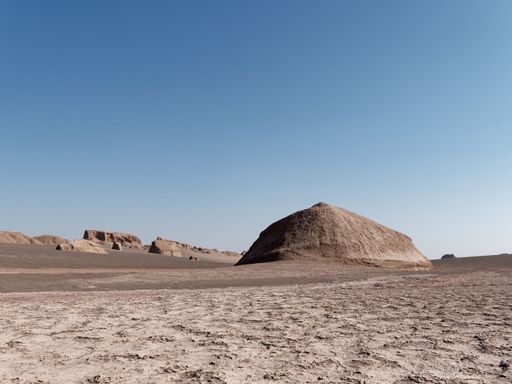 A majestic ancient pyramid stands in the middle of a vast desert landscape, its towering structure looming over the sandy terrain