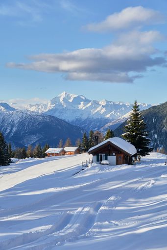 A vertical shot of the small huts nestled between the snowy mountains