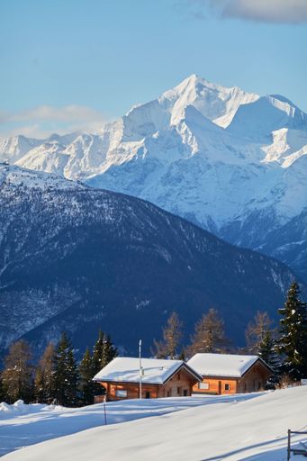 A vertical shot of the small huts nestled between the snowy mountains