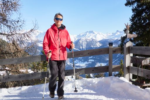 A hiker leaning on a fence in the Swiss Alps in snowy mountain landscape