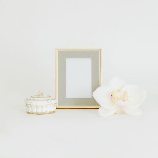 An isolated shot of empty golden frame mockup next to a jewelry box and orchid bud on white background