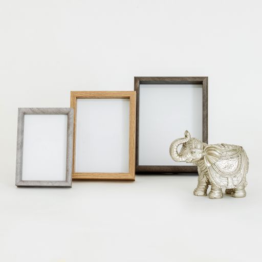 A closeup of three empty golden frame mockups in different sizes next to an elephant sculpture