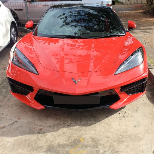 front view of luxury sports car red Chevrolet Corvette convertible parked outdoors on street