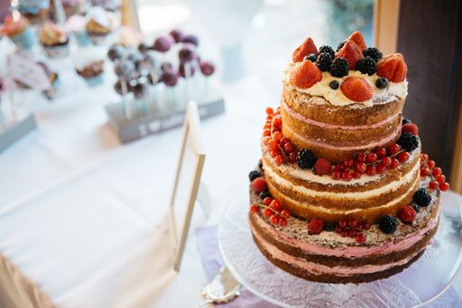 A closeup shot of a tiered cake decorated with fruits on the table with blur background