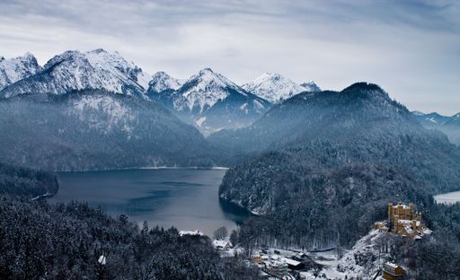 An aerial view of a historic castle in the snowy German Alps