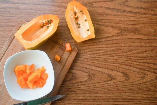 A top view of cut papaya on a wooden table with space for text