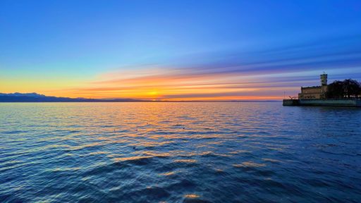 A stunning view of a distant island silhouetted against a beautiful orange and pink sky at sunset