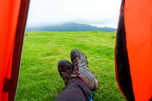 A male hiker's shoes in a tent on the grass in the countryside