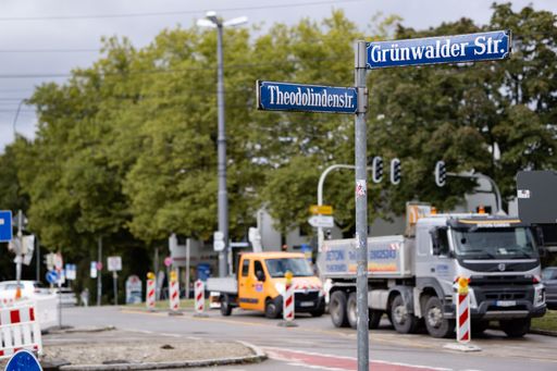 A construction sign shown on a street with a couple of large trucks in the background