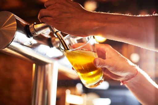 A vertical shot of a bartender dispensing beer into a glass at a pub