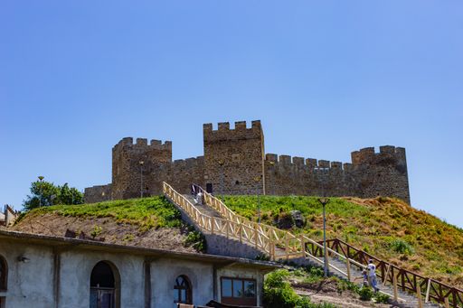 A  beautiful shot of a medieval castle standing on a hill in background of the clear blue sky