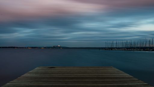 A scenic shot of a wooden dock on the sea in the evening, cool for background