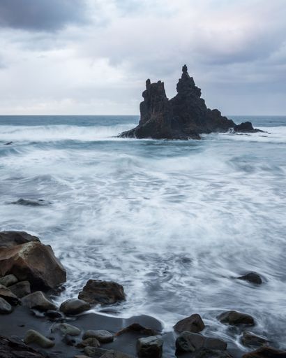 A beautiful coastal landscape featuring large rocky formations partially submerged in foamy water
