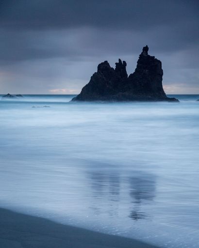 A beautiful coastal landscape featuring large rocky formations partially submerged in foamy water