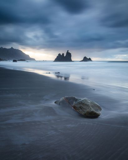 A beautiful coastal landscape featuring large rocky formations partially submerged in foamy water