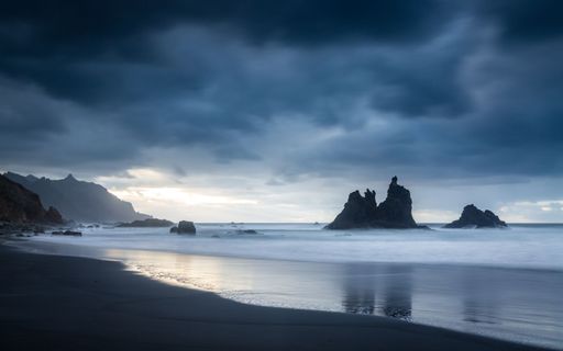 A beautiful coastal landscape featuring large rocky formations partially submerged in foamy water