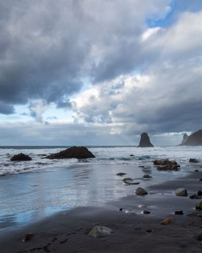 A beautiful coastal landscape featuring large rocky formations partially submerged in foamy water